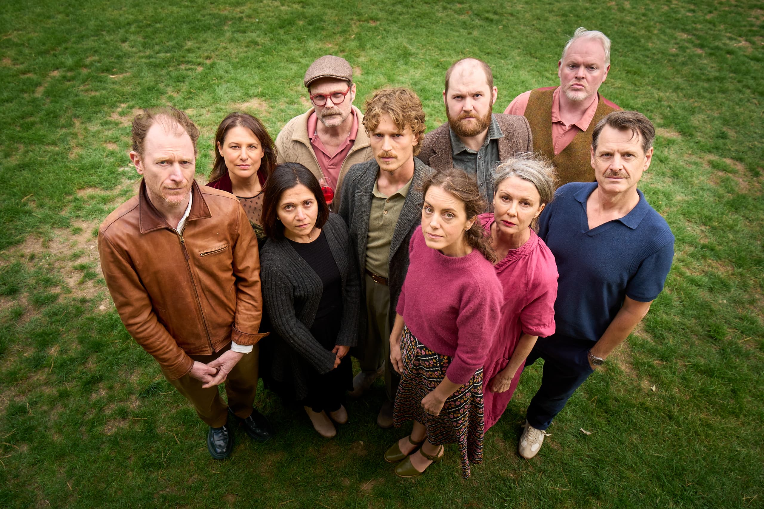 Ravens Theatre Company committee members standing together in front of a brick wall, smiling and looking up at the camera. Photo by Vincent Photography.